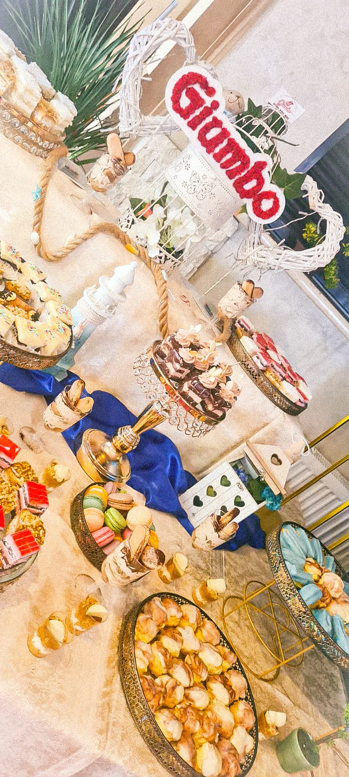 Masă dulce de eveniment pregătită de Cofetăria Giumbo, fotografiată de sus, cu prăjituri și decor pe platouri